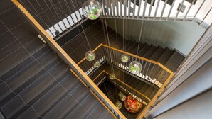 A modern staircase with a wooden frame and glass railings, featuring hanging spherical lights with greenery. - Waveboard Hotel & Boardinghouse  (Potsdam)