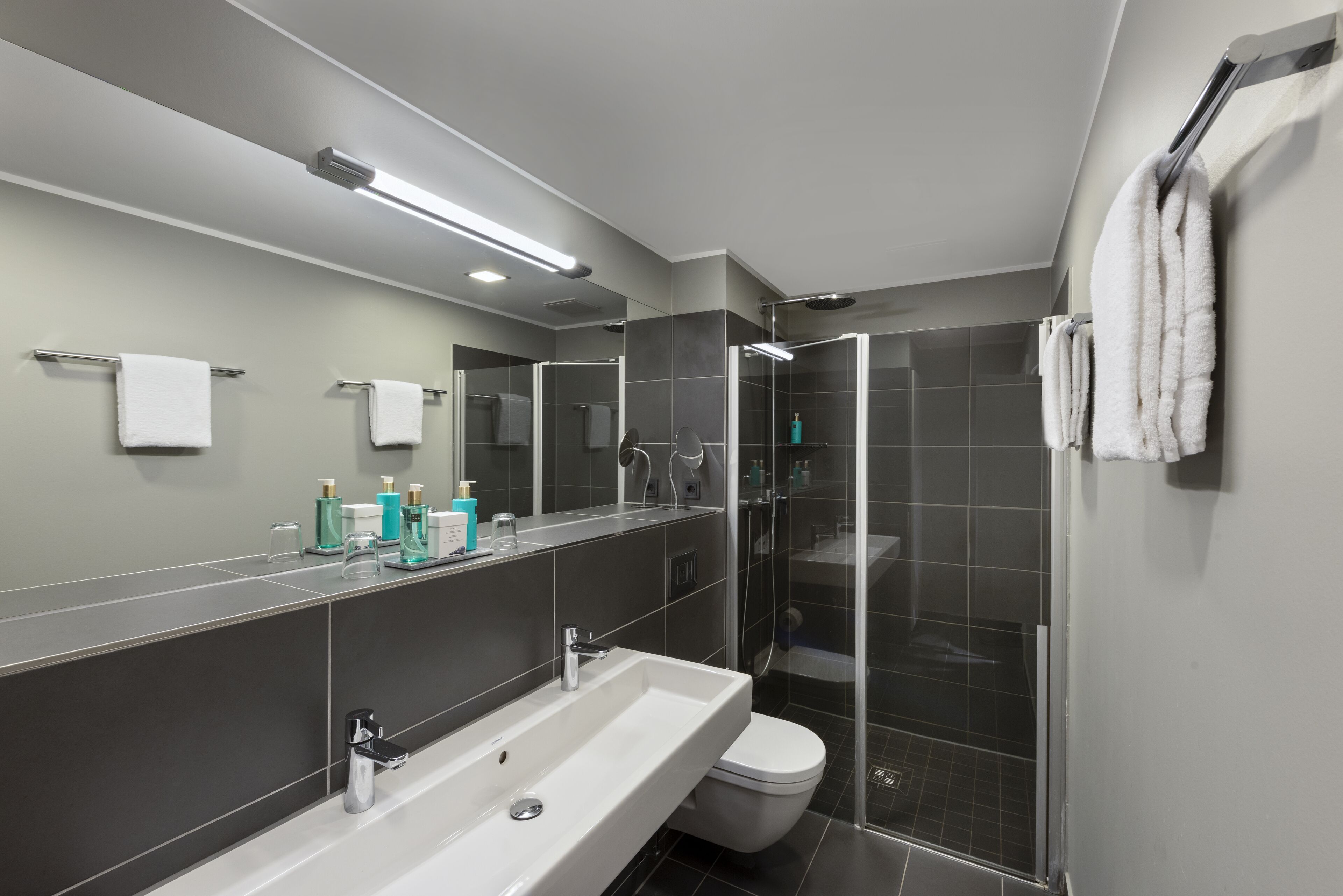 Un baño moderno con un lavamanos grande, espejo y cabina de ducha de vidrio.
