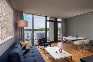A modern living room with a sofa, a coffee table, and a dining area with chairs and a table.