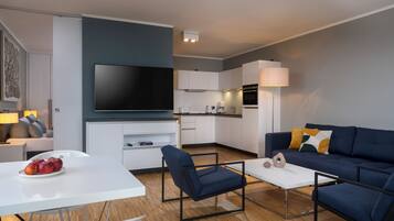 Un salon moderne avec un téléviseur à écran plat, un canapé, une table basse et un coin repas agrémenté de pommes.