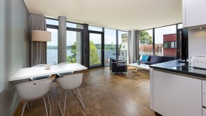 A modern kitchen with a dining area, large windows, and a view of a castle. - Waveboard Hotel & Boardinghouse  (Potsdam)