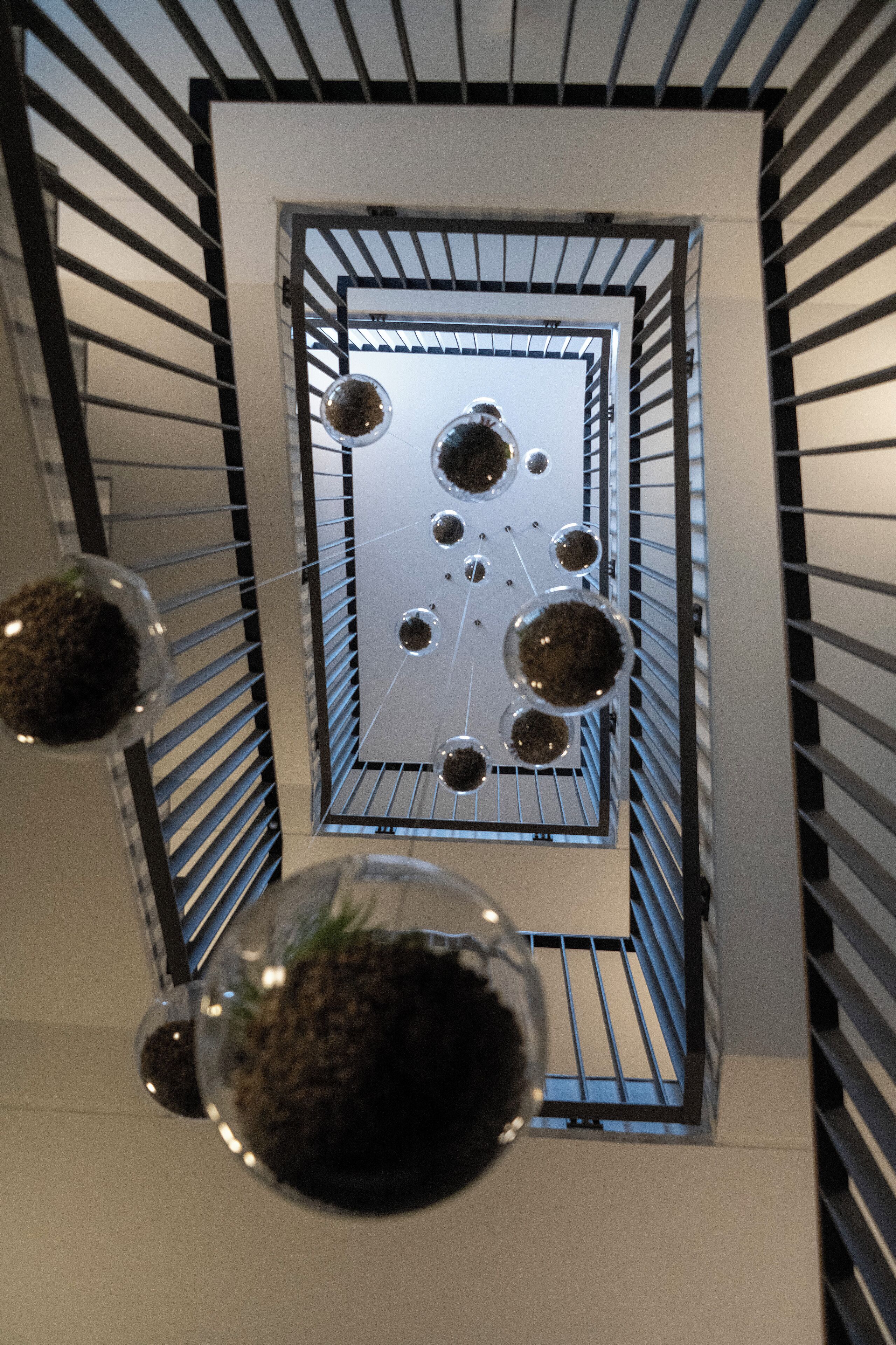 A modern interior with a geometric metal railing and spherical glass terrariums.