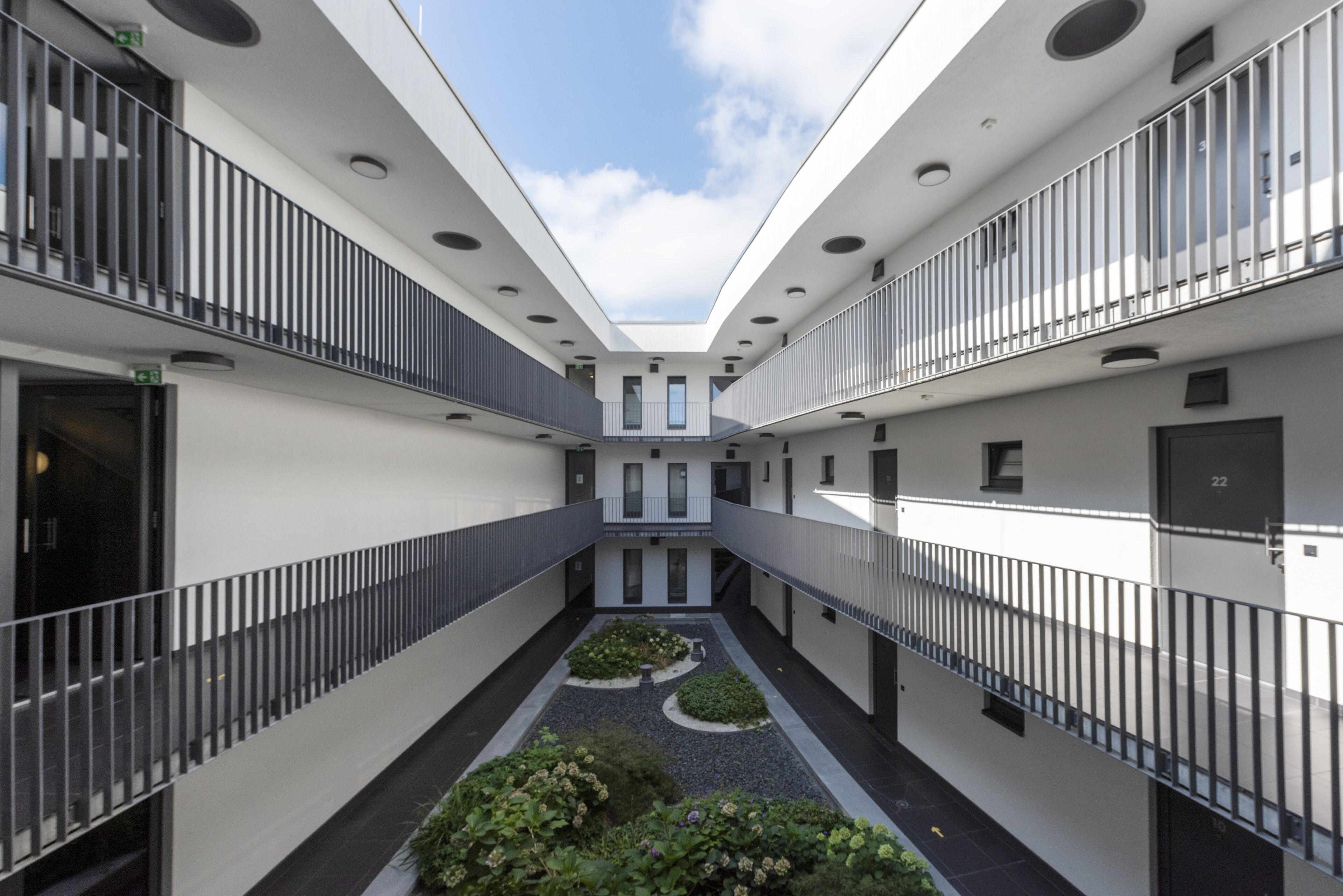 Un edifici modern amb un pati central, balcons i un cel clar.