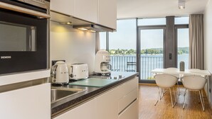 A modern kitchen with a Siemens oven, a coffee maker, and a view of a balcony with a table and chairs. - Waveboard Hotel & Boardinghouse  (Potsdam)