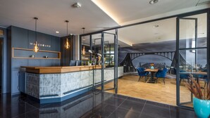 A modern hotel lobby with a reception desk, seating area, and large windows offering views of the city. - Waveboard Hotel & Boardinghouse  (Potsdam)