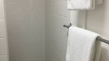 A small, tiled shower area with a tiled floor and a towel rack with two towels.