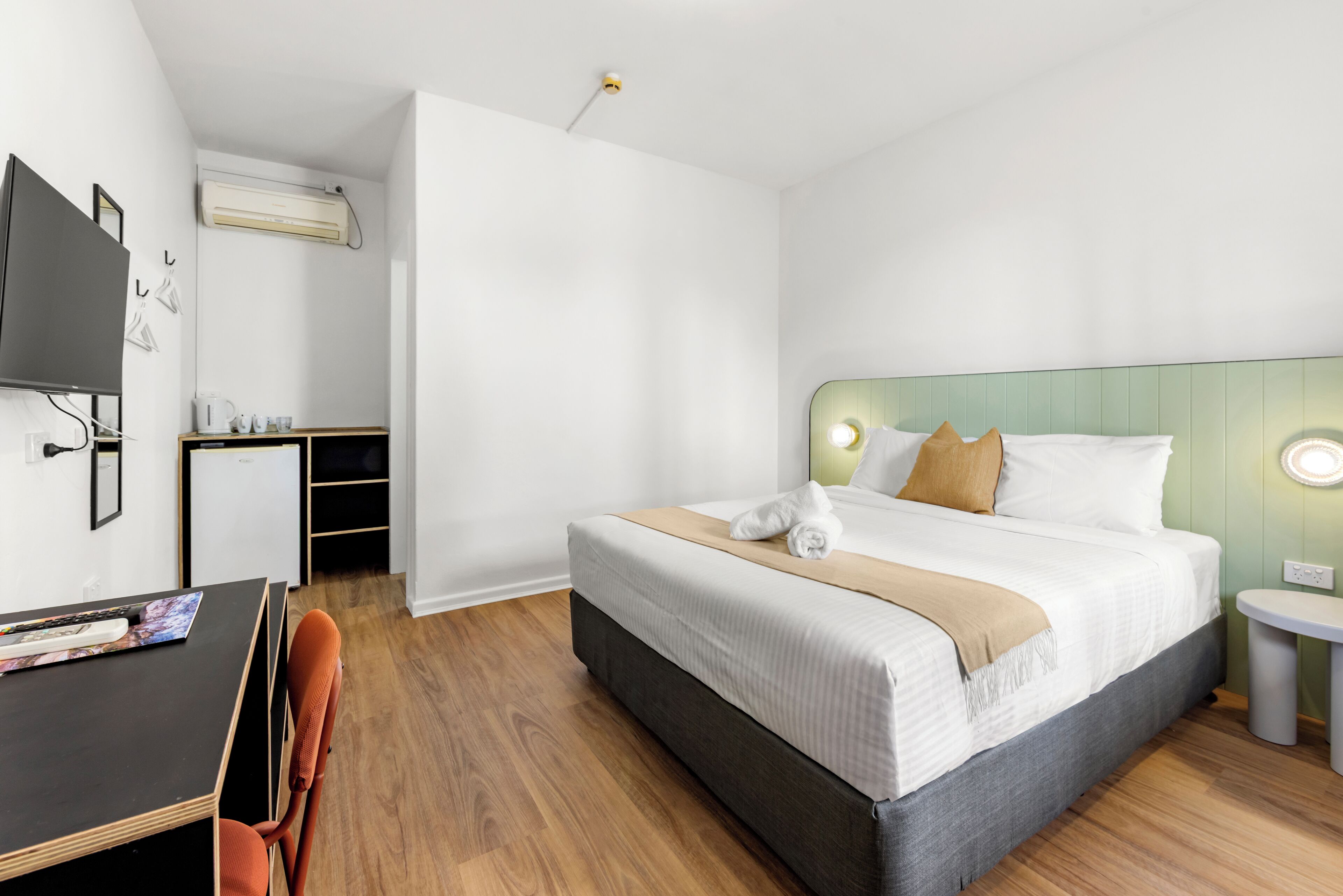 Una habitación de hotel con cama, escritorio, silla y televisión.