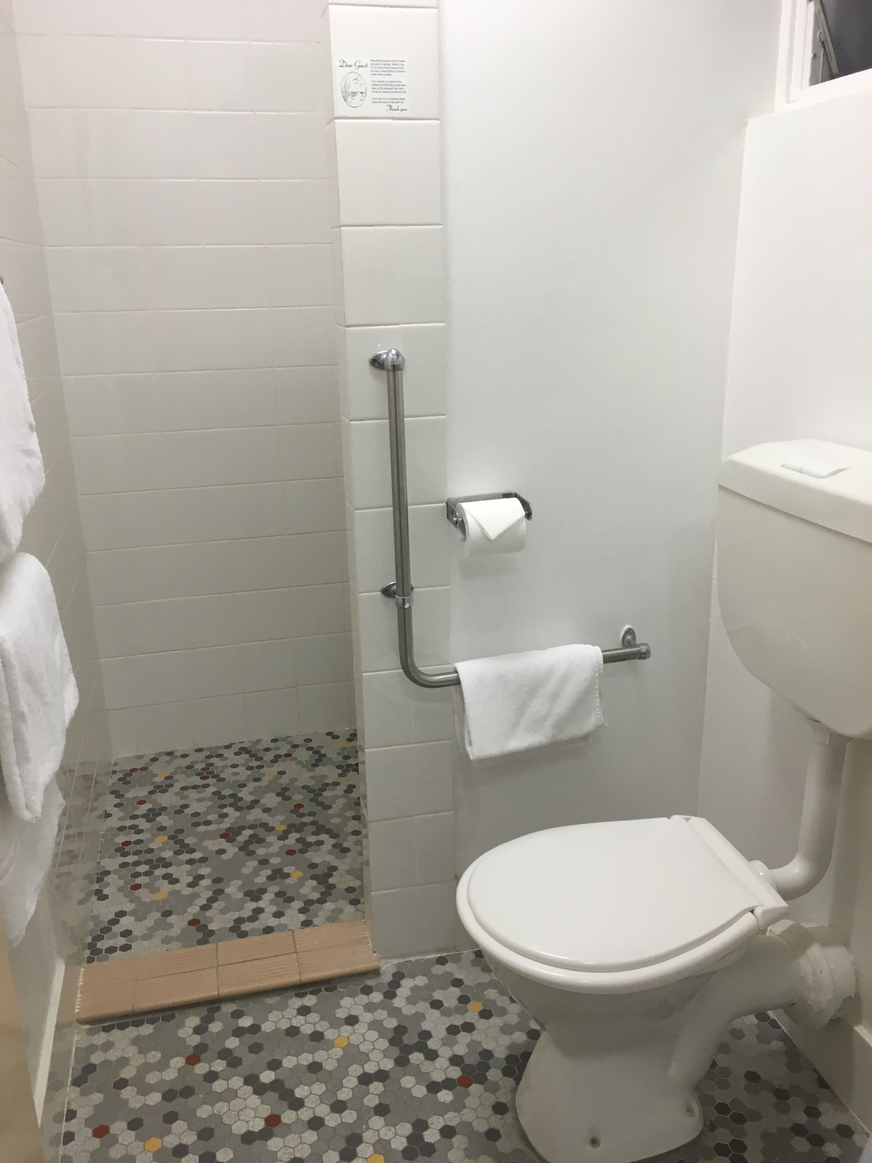 A bathroom with a toilet, a shower stall, and a toilet paper holder.