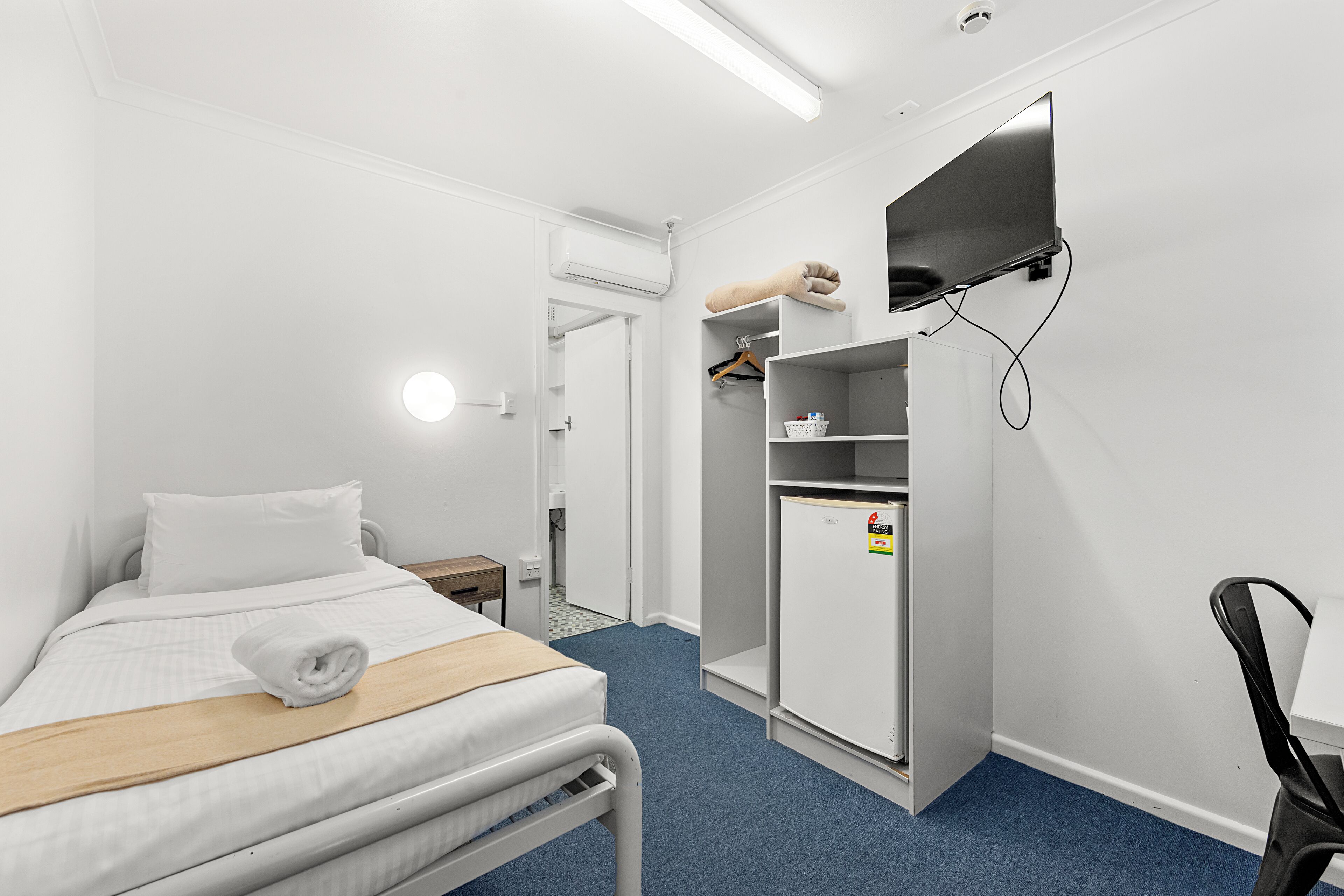 Een hotelkamer met een bed, bureau, kledingkast en televisie.