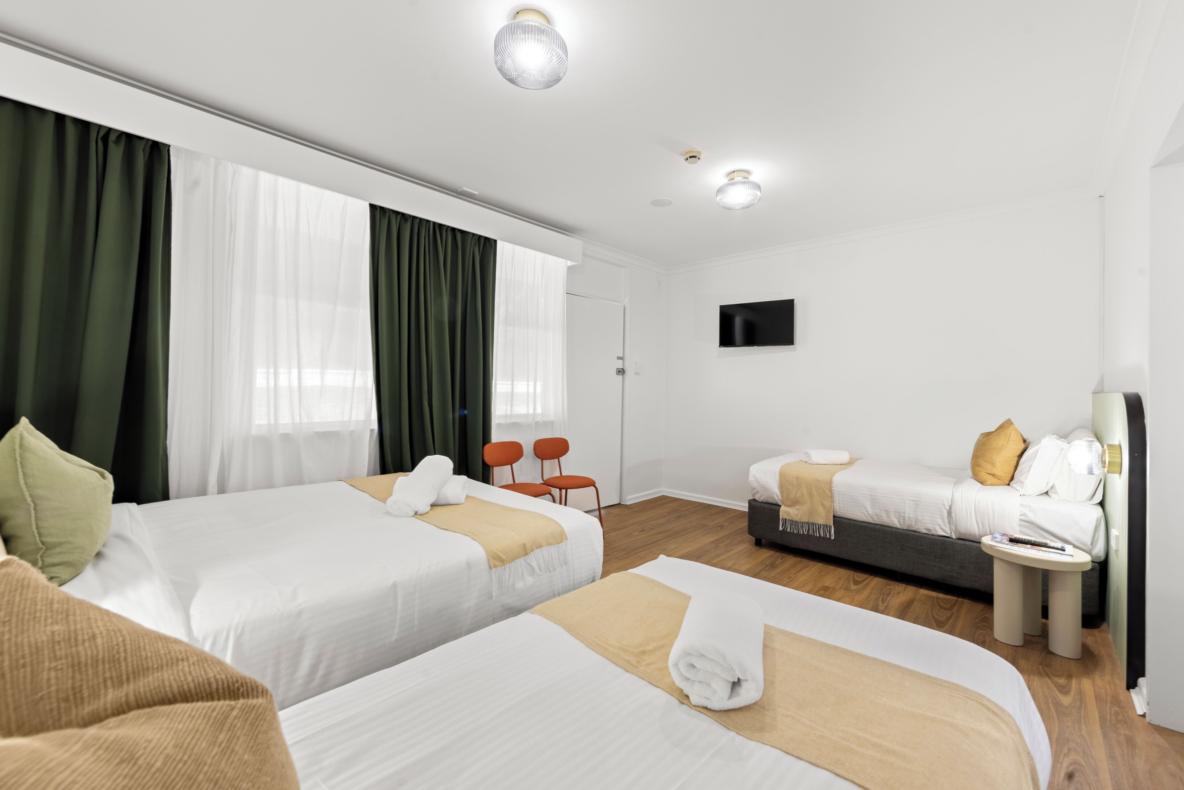 A hotel room with two beds, a TV, a small table, and a sofa.