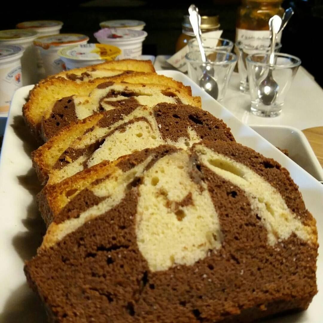 A loaf of marble cake with a white and brown swirl pattern, placed on a white plate.