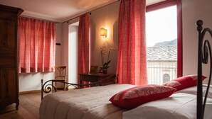 Un dormitorio con cama, mesita de noche, lámpara y ventana con cortinas.