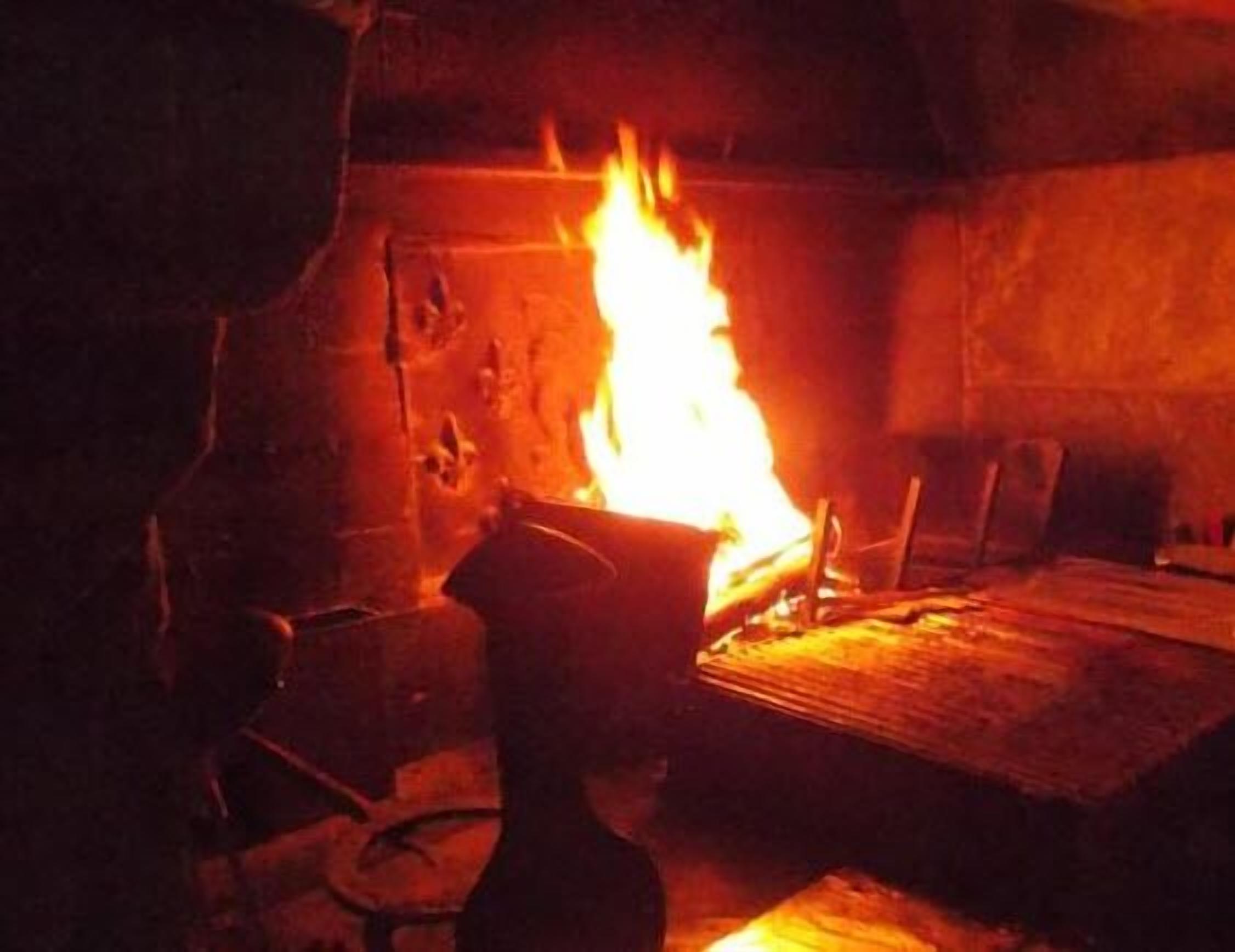 Una stanza con un ampio camino acceso, arredi in legno e una rustica parete in pietra.