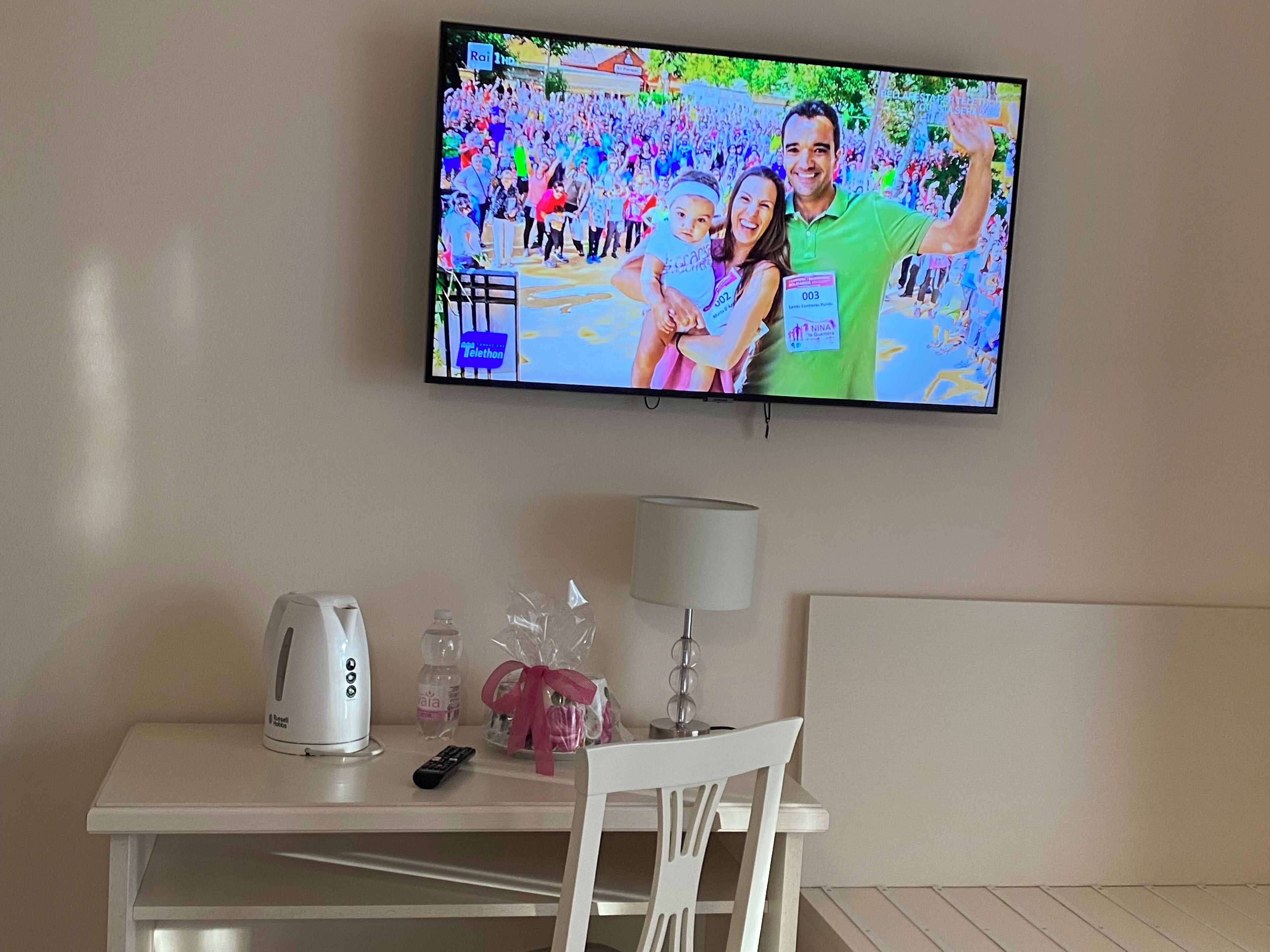 Un téléviseur fixé au mur diffusant des images d’un événement rassemblant une foule.