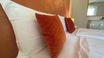 A neatly made bed with white linens and two large pillows, one with a textured pattern.