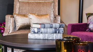 A round table with a stack of books and three metallic candle holders.