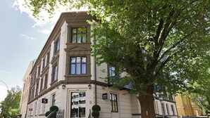 A multi-story hotel with a classic architectural style, featuring a grand entrance with steps and a small garden area. - Saga Apartments Oslo (Oslo)
