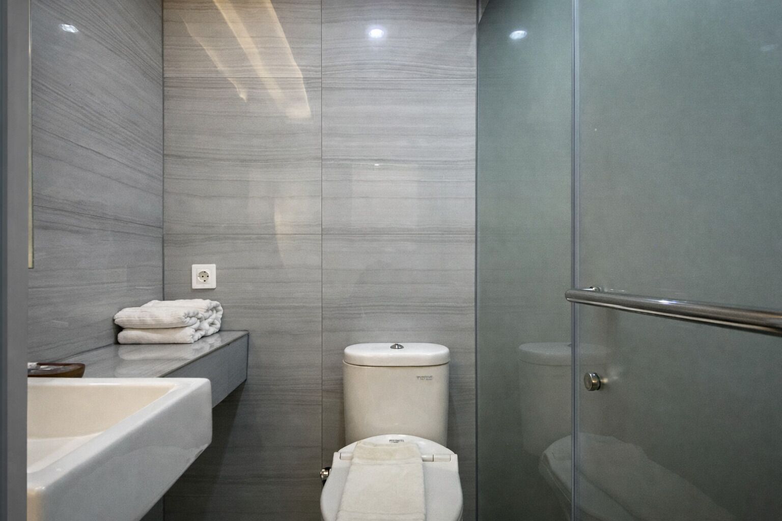 A modern bathroom with a bathtub, toilet, and glass shower enclosure.