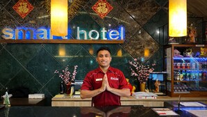 A hotel reception desk with a name sign, a name tag, and a 'For Sale' sign.