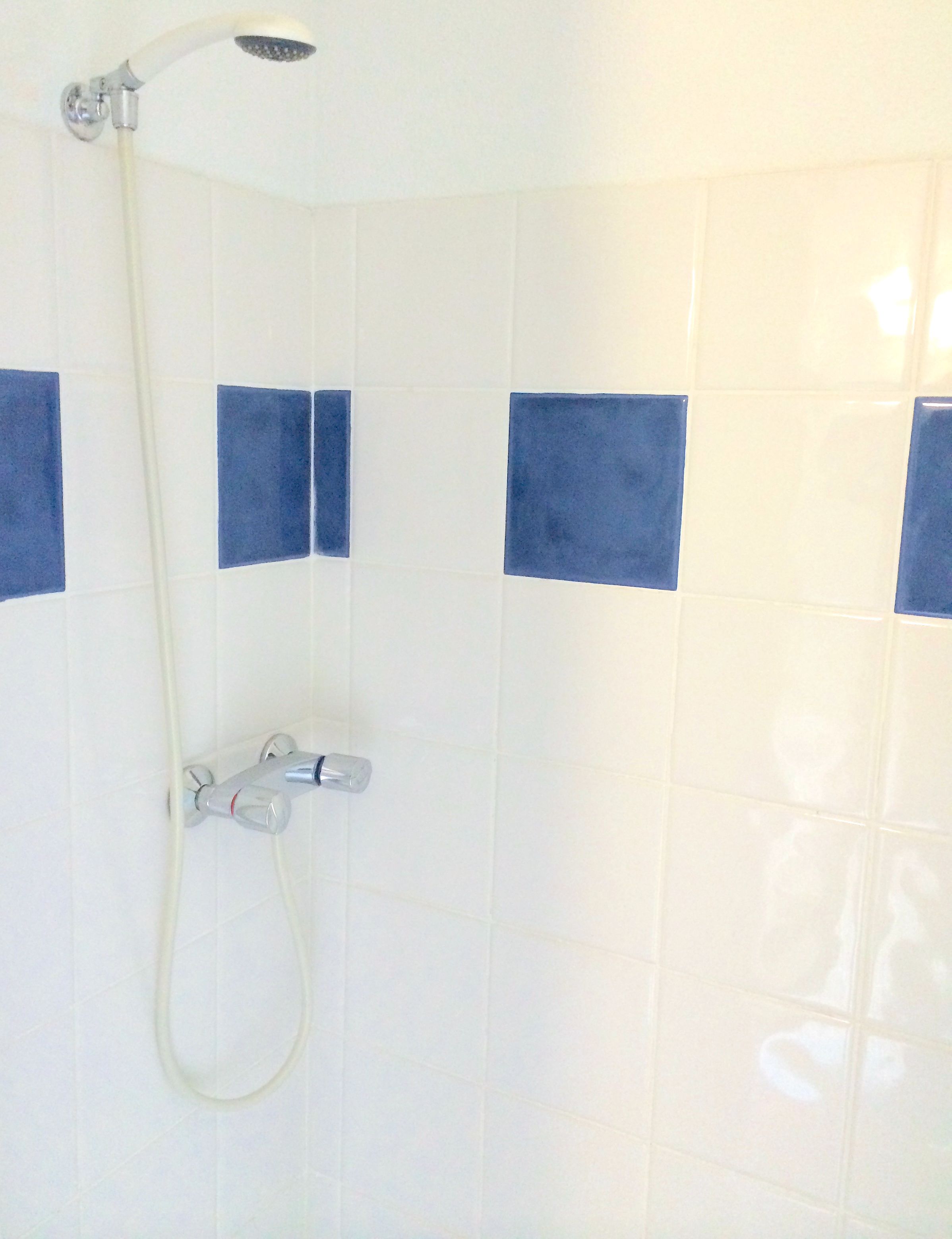 Un espace douche équipé d’un pommeau de douche à main et d’un robinet fixé au mur.
