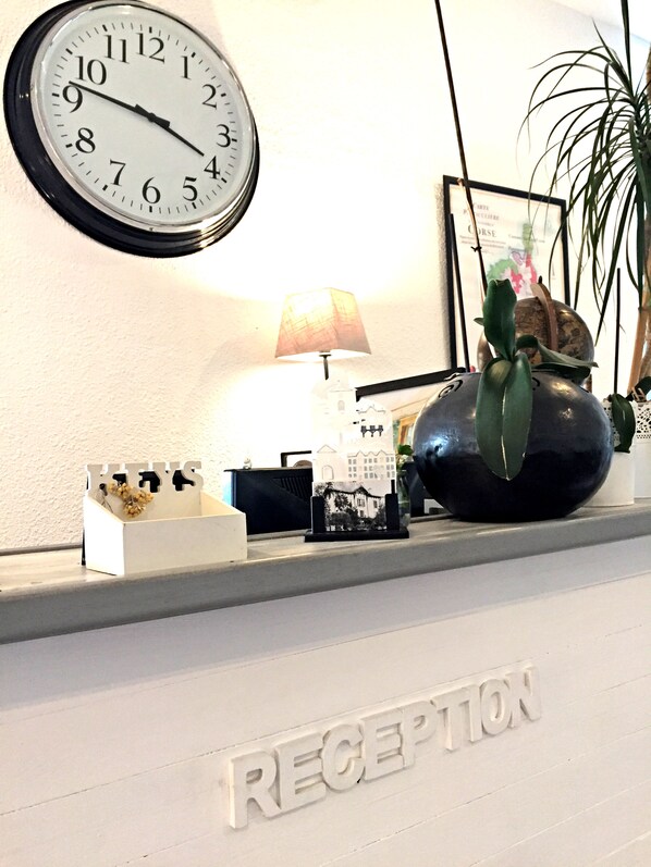 Una mesa de recepción con un reloj, una lámpara y una decoración de cactus.
