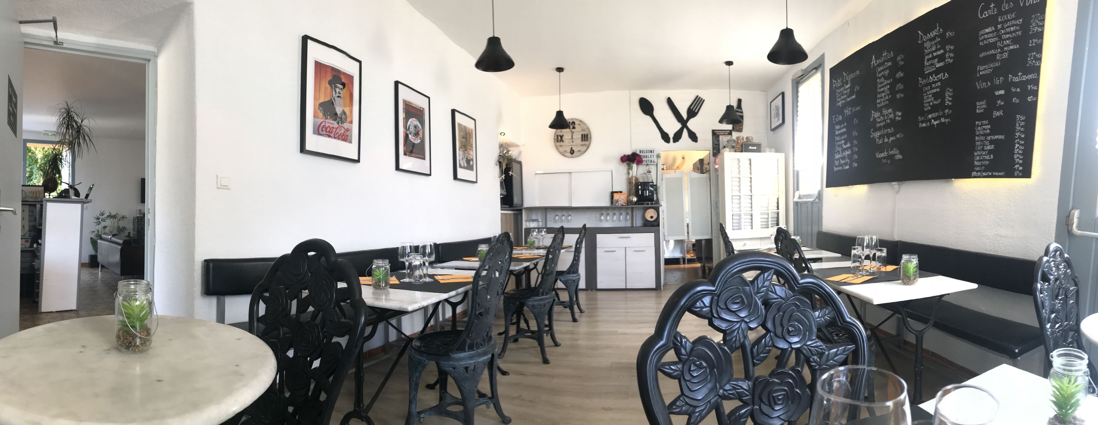 Un restaurante con decoración en blanco y negro, que incluye cuadros enmarcados, un reloj y un menú en la pared.