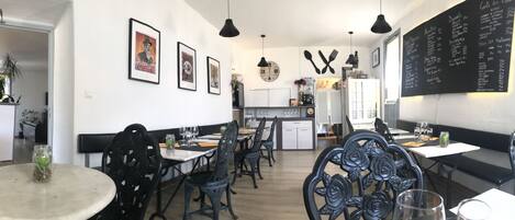 Un restaurante con decoración en blanco y negro, que incluye cuadros enmarcados, un reloj y un menú en la pared.