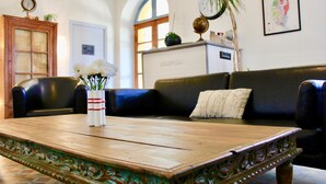 Una zona de recepción con una mesa de madera, un sofá de cuero negro y un globo terráqueo en una estantería.