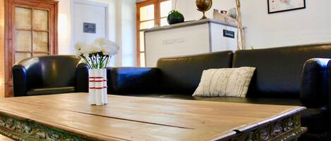 Una zona de recepción con una mesa de madera, un sofá de cuero negro y un globo terráqueo en una estantería.