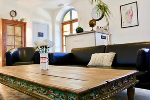 Una zona de recepción con una mesa de madera, un sofá de cuero negro y un globo terráqueo en una estantería.