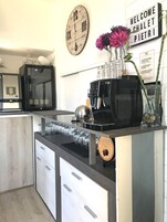 Una cocina moderna con cafetera, un reloj y un cartel de bienvenida.