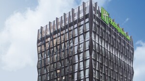A modern building with a unique wavy facade, a green sign indicating it's a Holiday Inn Express, and a lower level with a covered walkway. - Holiday Inn Nanjing Qinhuai South Suites by IHG (Nanjing)