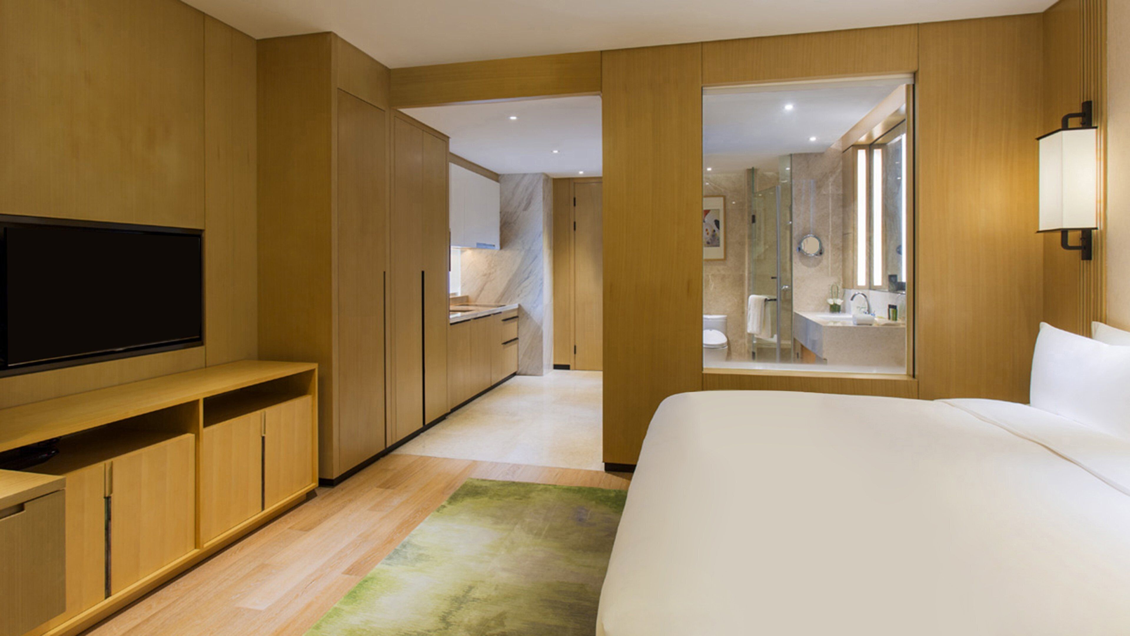 Habitación de hotel con una cama grande, armario de madera, televisor y baño visible a través de una puerta de cristal.