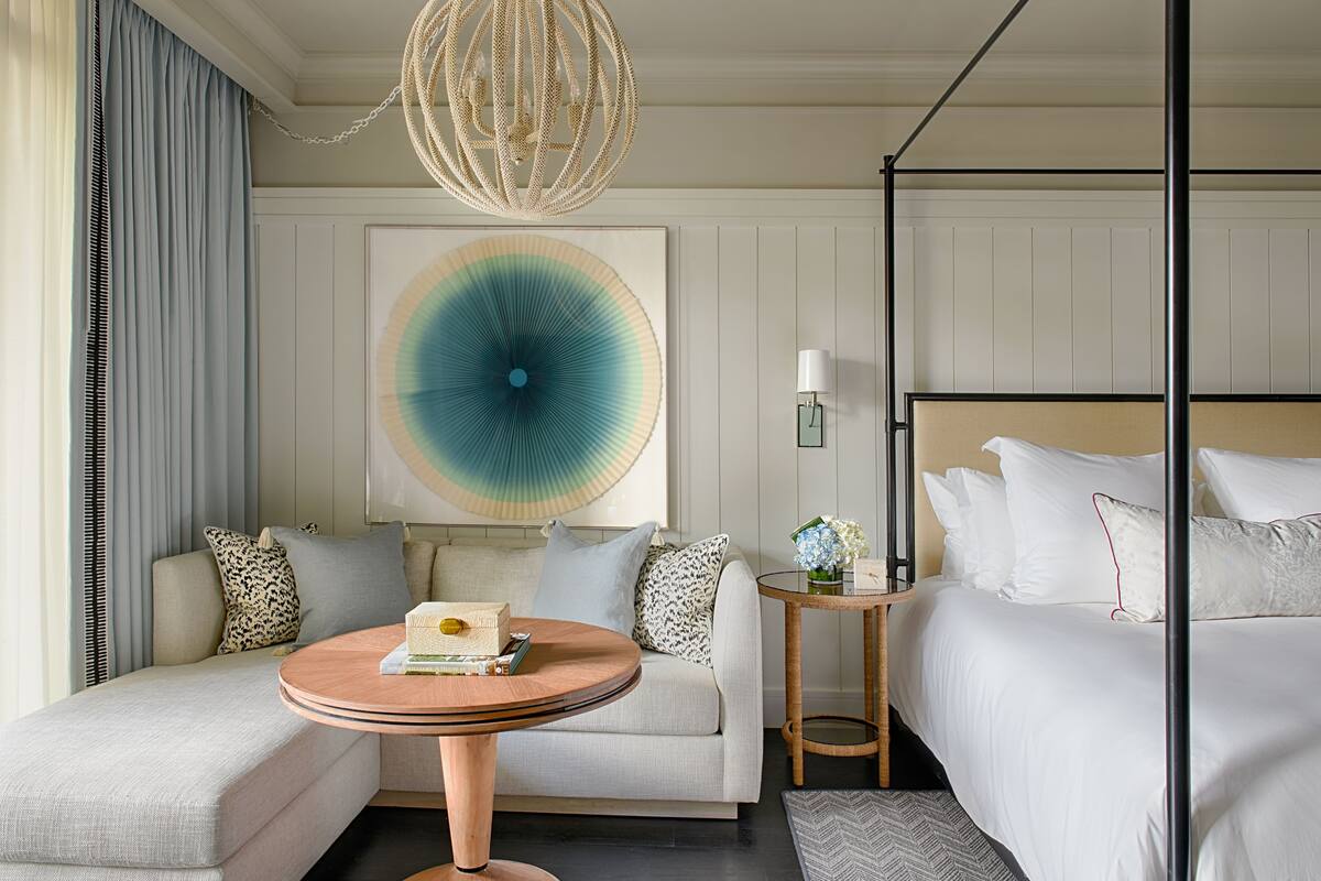 Een hotelkamer met een bed, een bank, een ronde tafel en een groot abstract schilderij aan de muur.