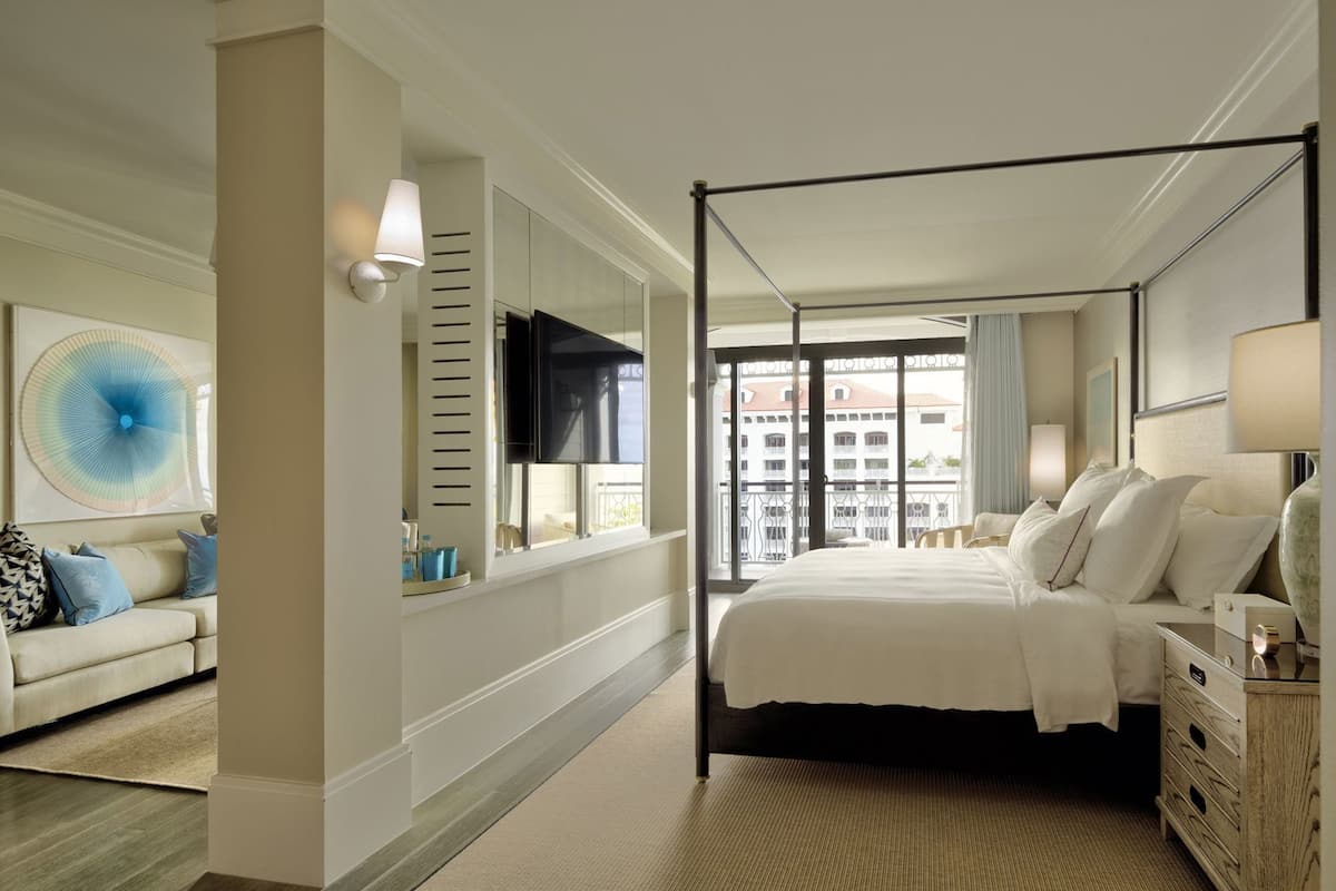 Een hotelkamer met een groot bed, een televisie, een bank en uitzicht op gebouwen.