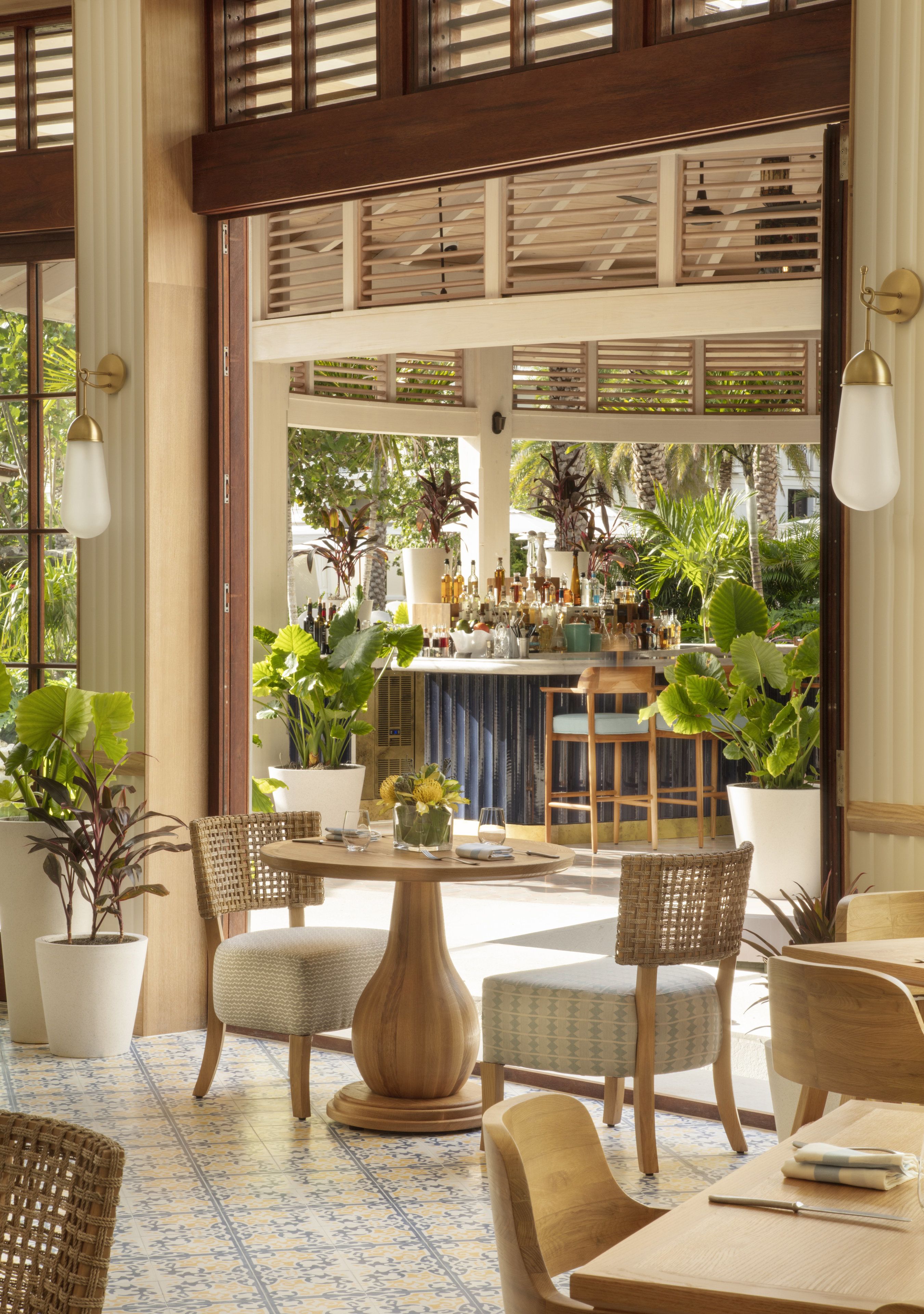 A spacious indoor area with a bar, multiple seating arrangements, and potted plants.