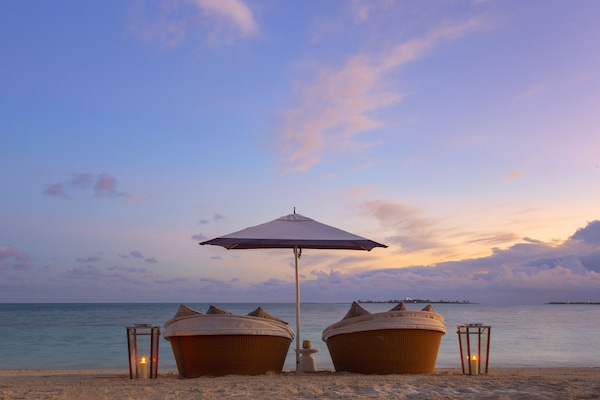 Di pantai, pasir putih, kursi berjemur, dan payung pantai