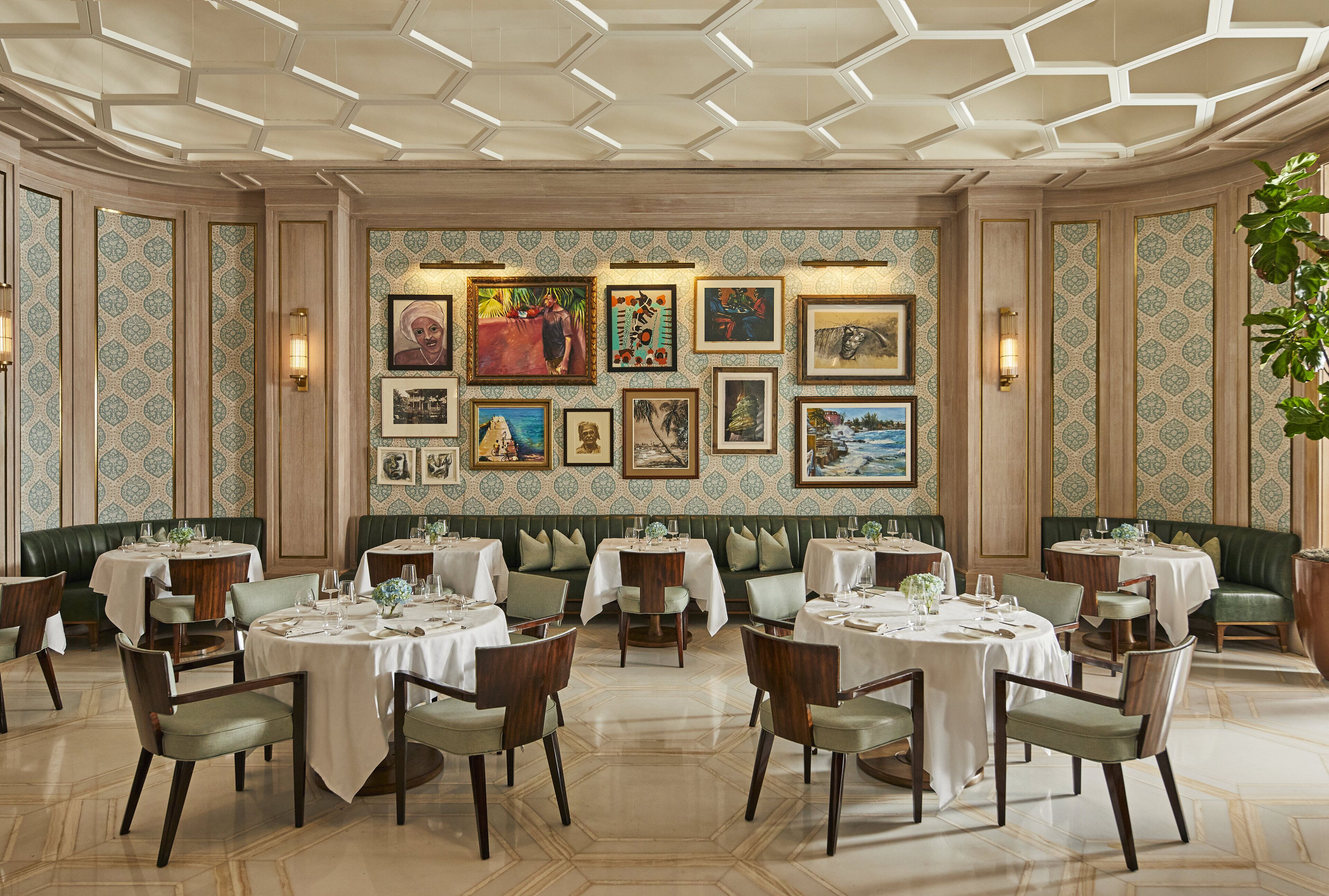 A dining area with round tables, green upholstered booths, and framed artwork on the walls.