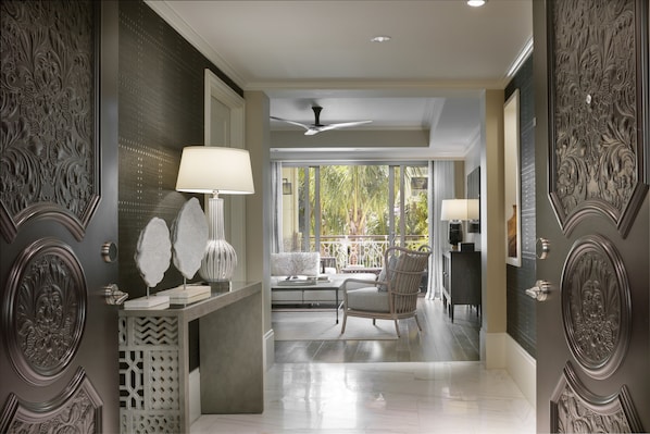 A modern interior with a decorative wall, a seating area with a chair, and a view through large windows.