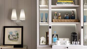 Una habitación con un armario blanco con puertas de vidrio, un cuadro en la pared y una silla de madera.