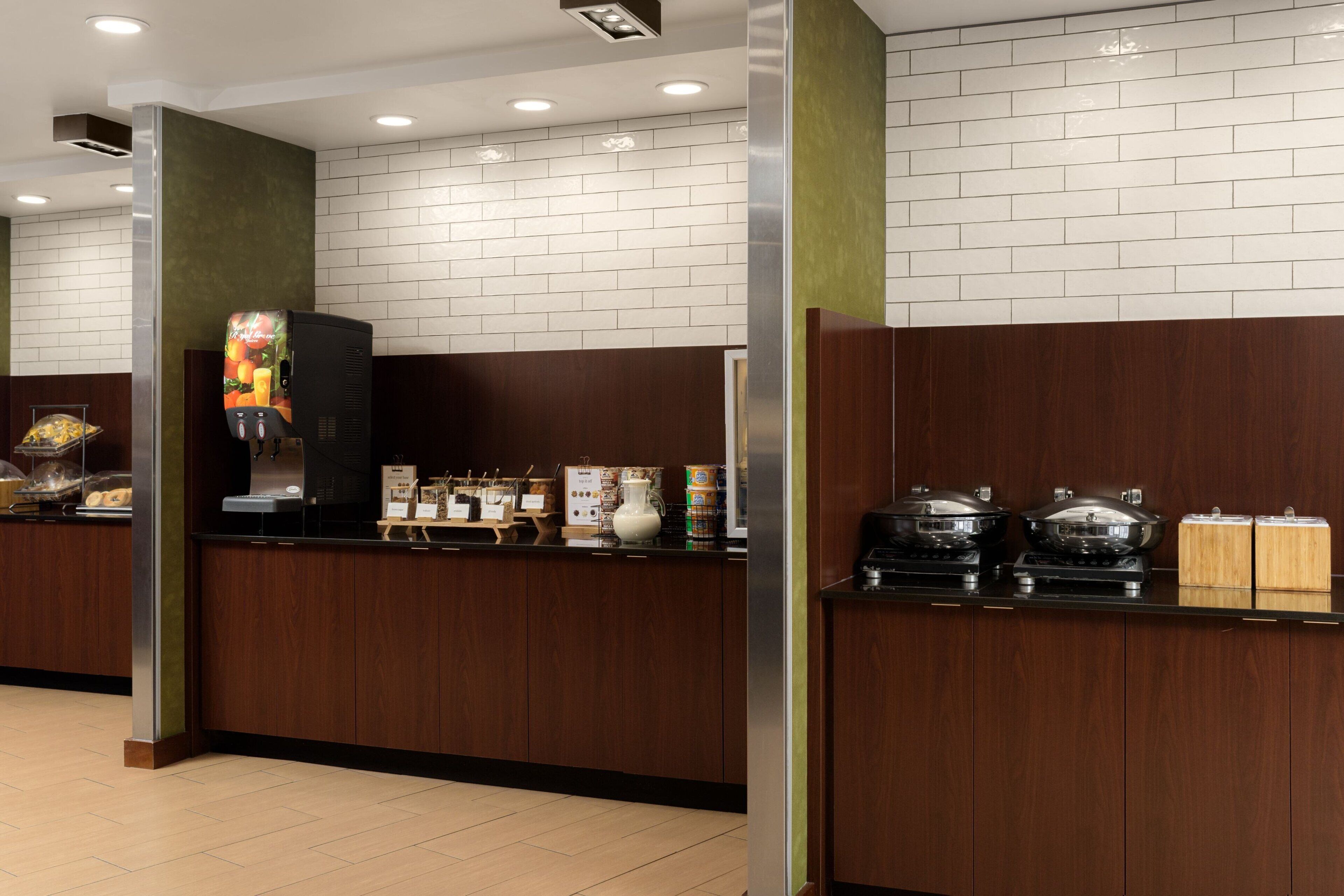A modern kitchen area with wooden cabinets, a coffee machine, and a display of food items.