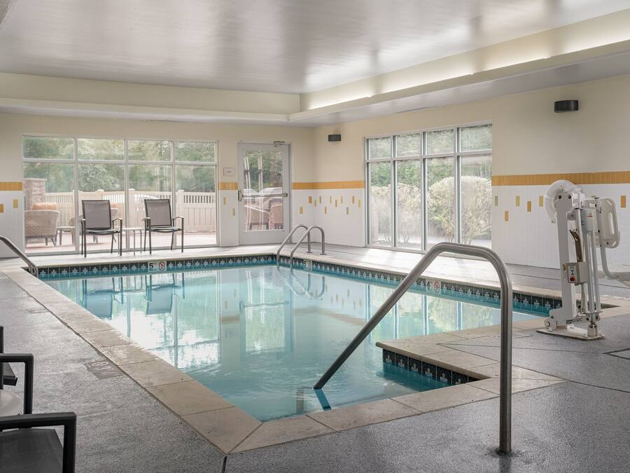 An indoor swimming pool with clear water, surrounded by tiled walls and windows.