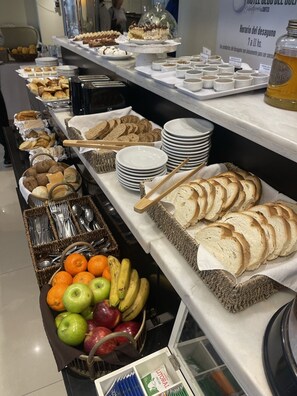 A buffet with various food items including bread, pastries, fruits, and condiments. - Hotel Club del Golf (Mar del Plata)