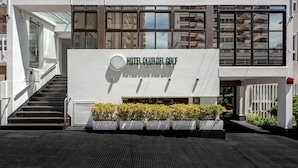 A modern building with a sign reading "HOTEL CLUB DEL GOLF".