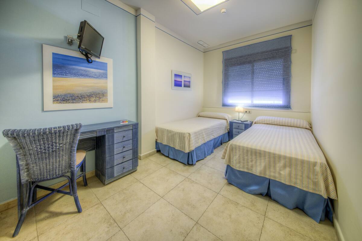 A room with two beds, a desk, and a chair.