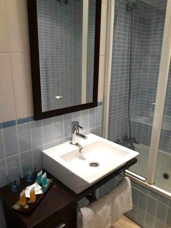 Une salle de bain avec un lavabo blanc, un miroir et un espace douche.