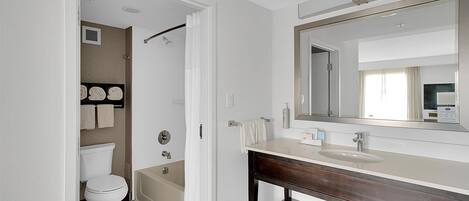 Une salle de bain moderne avec des toilettes, une baignoire et un grand miroir au-dessus du lavabo.