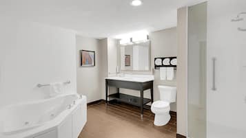 A modern bathroom with a bathtub, a sink, a toilet, and a glass shower enclosure.