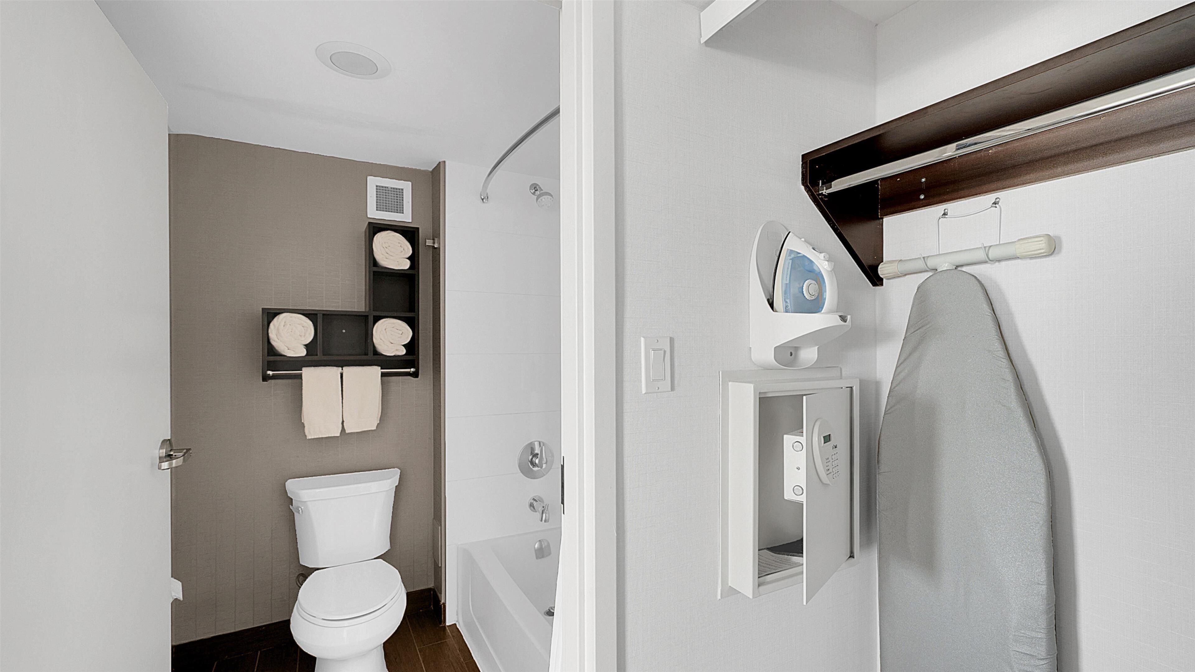 A modern bathroom with a toilet, shower, and built-in towel rack.