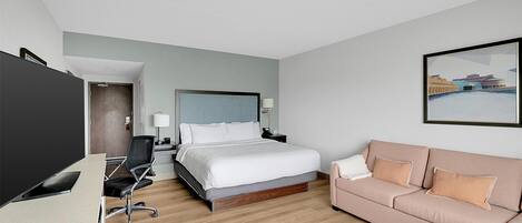 Ein Hotelzimmer mit einem Bett, einem Schreibtisch, einem Sessel, einer Couch und einem Bild an der Wand.